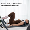 Beige Pilates Grip Socks mit rutschfester Sohle aus bordeauxfarbenen Herz-Noppen, getragen auf einem Reformer beim Training. Ideal für Reformer Pilates, Yoga und Barre.