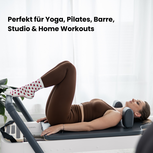 Beige Pilates Grip Socks mit rutschfester Sohle aus bordeauxfarbenen Herz-Noppen, getragen auf einem Reformer beim Training. Ideal für Reformer Pilates, Yoga und Barre.