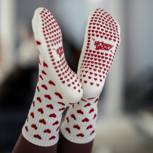 Detailansicht der Sohle: beigefarbene Pilates Socken mit roten Herz-Grip-Noppen und grippyglow Logo – funktional & cute zugleich