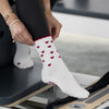 Beige Pilates Grip Socks mit bordeauxroten Herzmustern und rutschfestem Profil, getragen auf einem Reformer. Ideal für Pilates, Yoga und Barre.