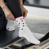 Beige Pilates Grip Socks mit bordeauxroten Herzmustern und rutschfestem Profil, getragen auf einem Reformer. Ideal für Pilates, Yoga und Barre.