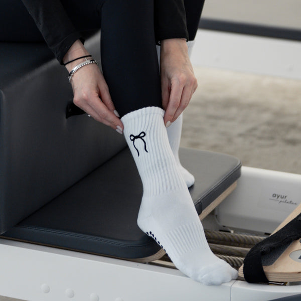 Weiße Pilates Grip Socks mit schwarzer Schleifen-Stickerei – stylische Anti-Rutsch Socken für Reformer Pilates auf dem Trainingsgerät