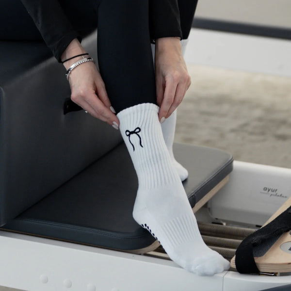 Weiße Pilates Grip Socks mit schwarzer Schleifen-Stickerei – stylische Anti-Rutsch Socken für Reformer Pilates auf dem Trainingsgerät