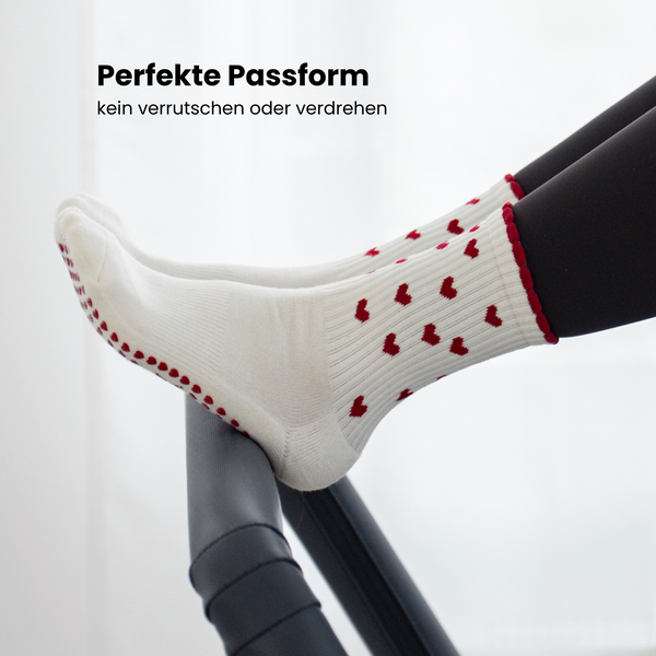 Beige Pilates Grip Socks mit rutschfester Sohle aus bordeauxfarbenen Herz-Noppen, getragen auf einem Reformer beim Training. Ideal für Reformer Pilates, Yoga und Barre.