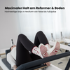 Beige Pilates Grip Socks mit rutschfester Sohle aus bordeauxfarbenen Herz-Noppen, getragen auf einem Reformer beim Training. Ideal für Reformer Pilates, Yoga und Barre.