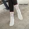 Beige Pilates Grip Socks mit rutschfester Sohle aus bordeauxfarbenen Herz-Noppen, getragen auf einem Reformer beim Training. Ideal für Reformer Pilates, Yoga und Barre.