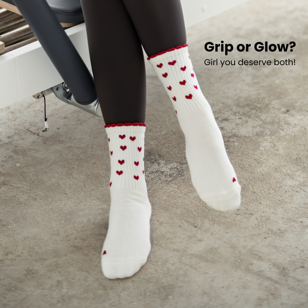 Beige Pilates Grip Socks mit rutschfester Sohle aus bordeauxfarbenen Herz-Noppen, getragen auf einem Reformer beim Training. Ideal für Reformer Pilates, Yoga und Barre.