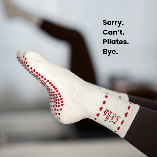 Beigefarbene Pilates Socken mit rutschfesten roten Herz-Noppen und grippyglow Logo – stylische Grip Socks für sicheren Halt im Reformer Studio