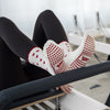 Beige Pilates Grip Socks mit rutschfester Sohle aus bordeauxfarbenen Herz-Noppen, getragen auf einem Reformer beim Training. Ideal für Reformer Pilates, Yoga und Barre.